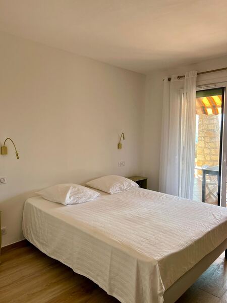 Chambre double lumineuse de la villa avec lit blanc et fenêtre sur la verdure