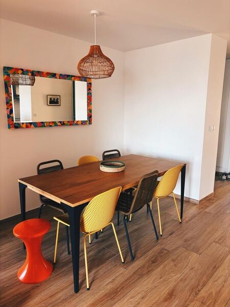 Salle à manger de la villa avec table en bois, chaises jaunes et miroir coloré