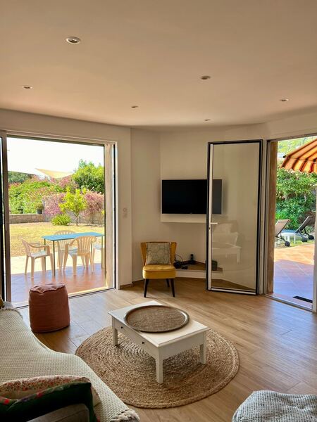 Salon de la villa avec canapé, tapis rond et accès à la terrasse et au jardin
