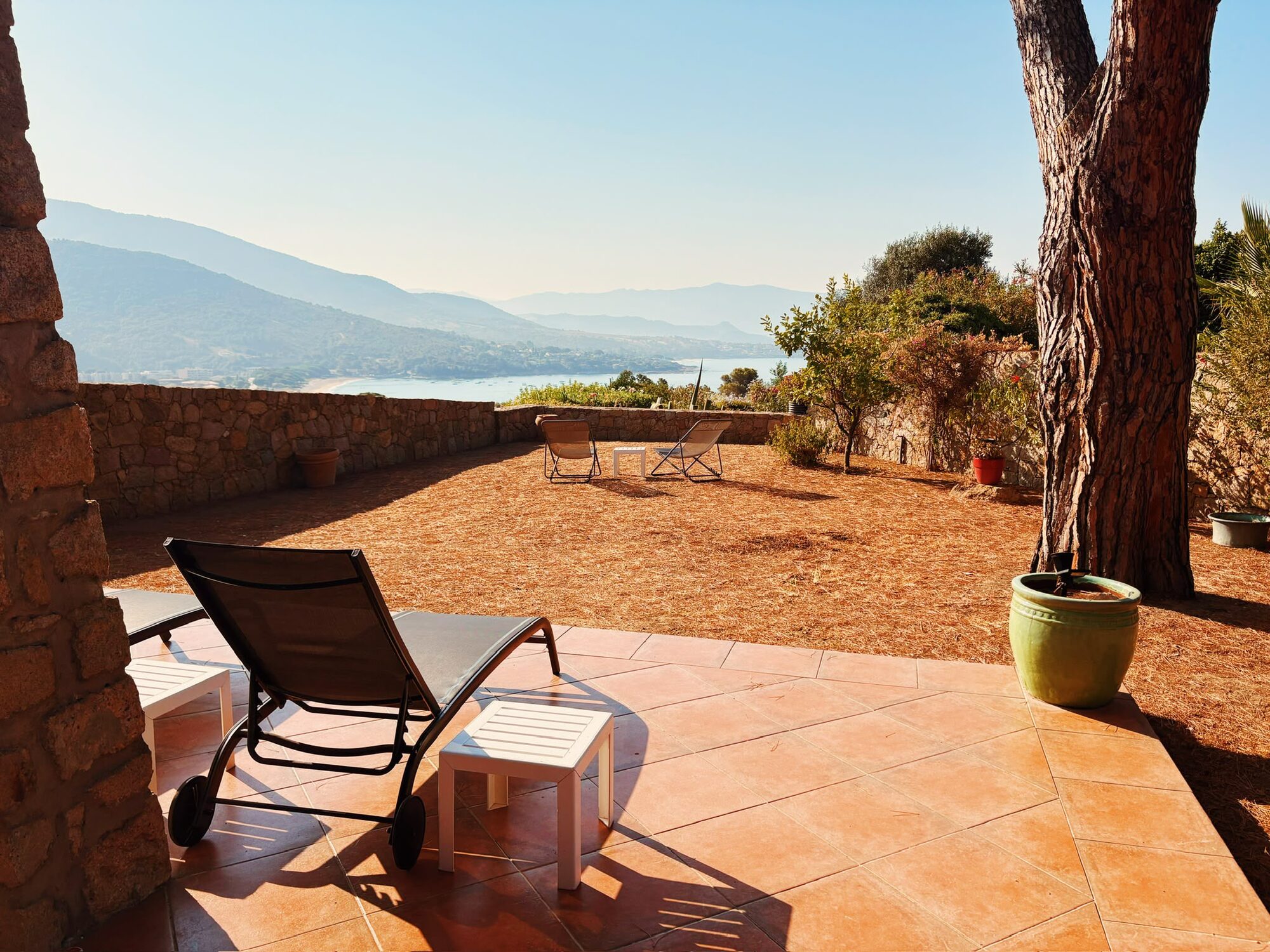 Transats sur la terrasse à l'ombre du pin parasol, avec vue sur la plage et le golfe de Sagone