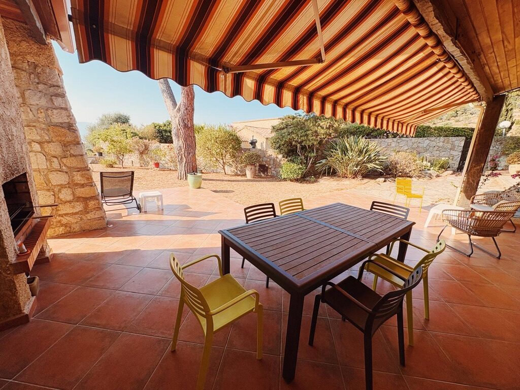 Terrasse der Villa in Sagone unter der Markise mit Tisch und Gartenblick